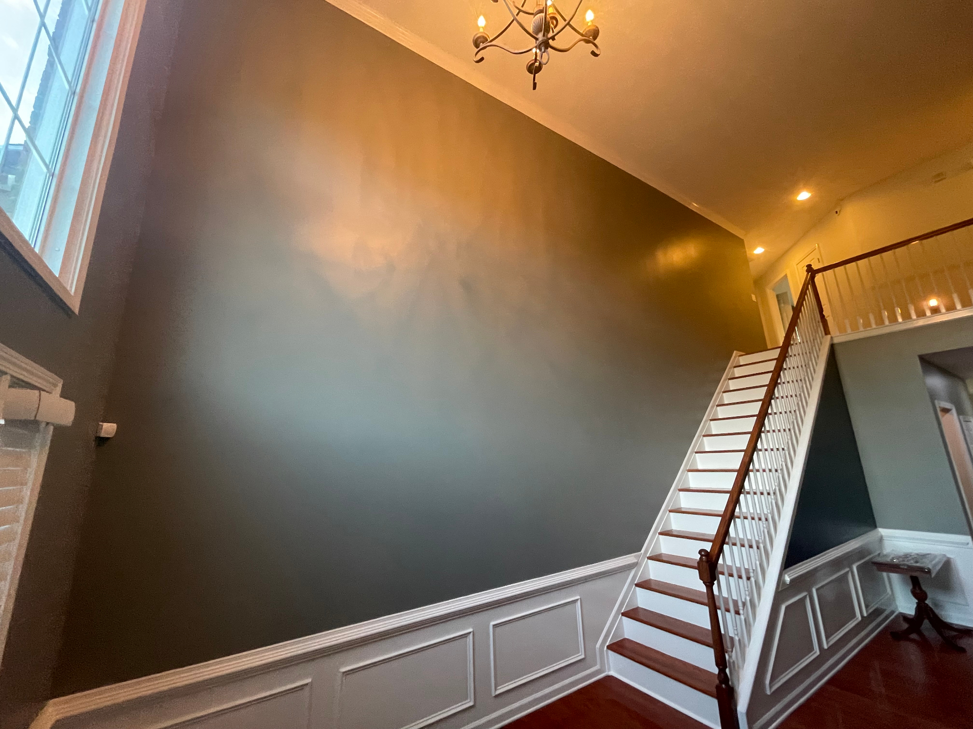 Two-story foyer with dark accent wall, white wainscoting, and stained staircase