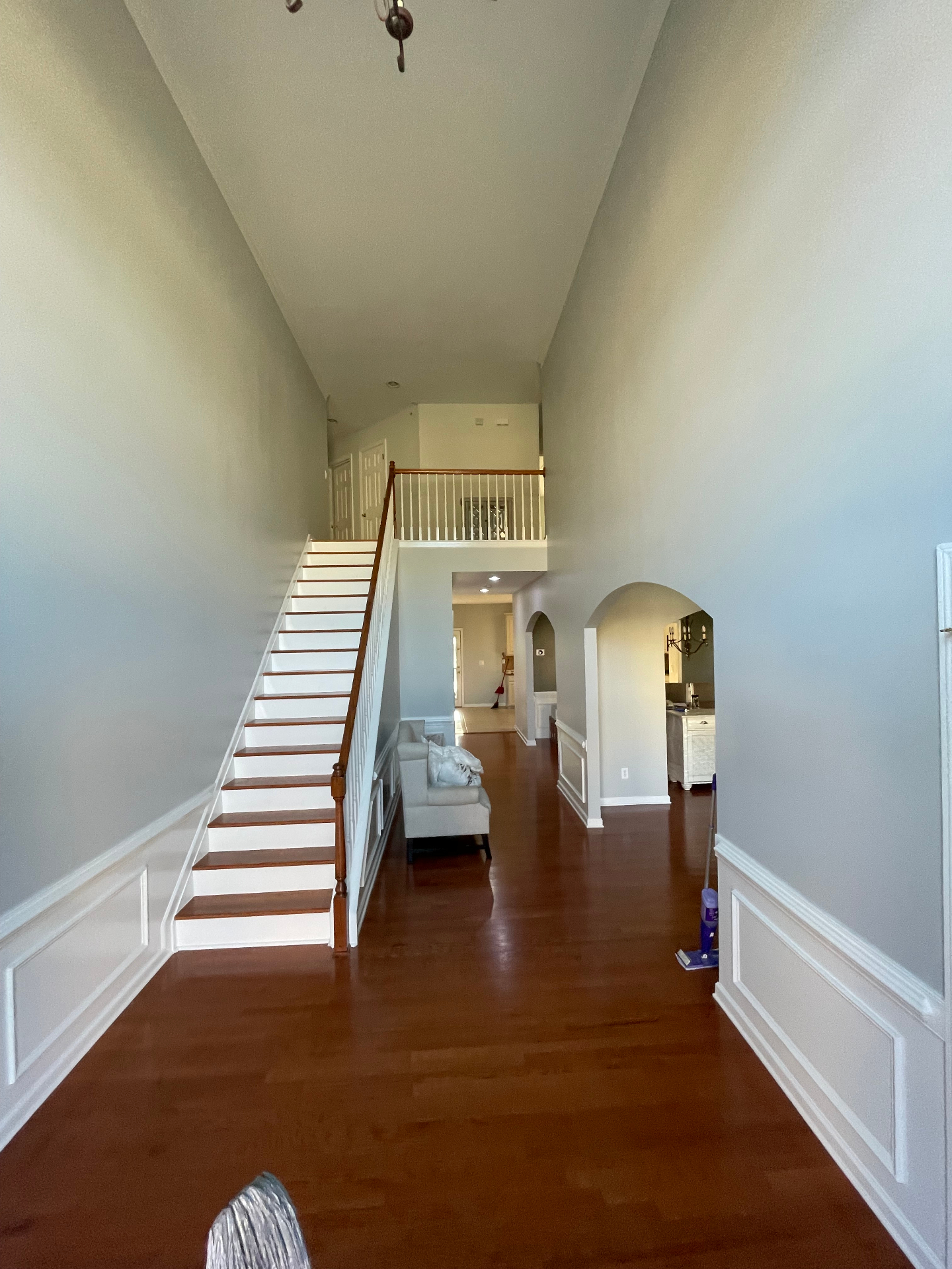 Two-story foyer after repaint with soft gray walls and refinished hardwood stairs