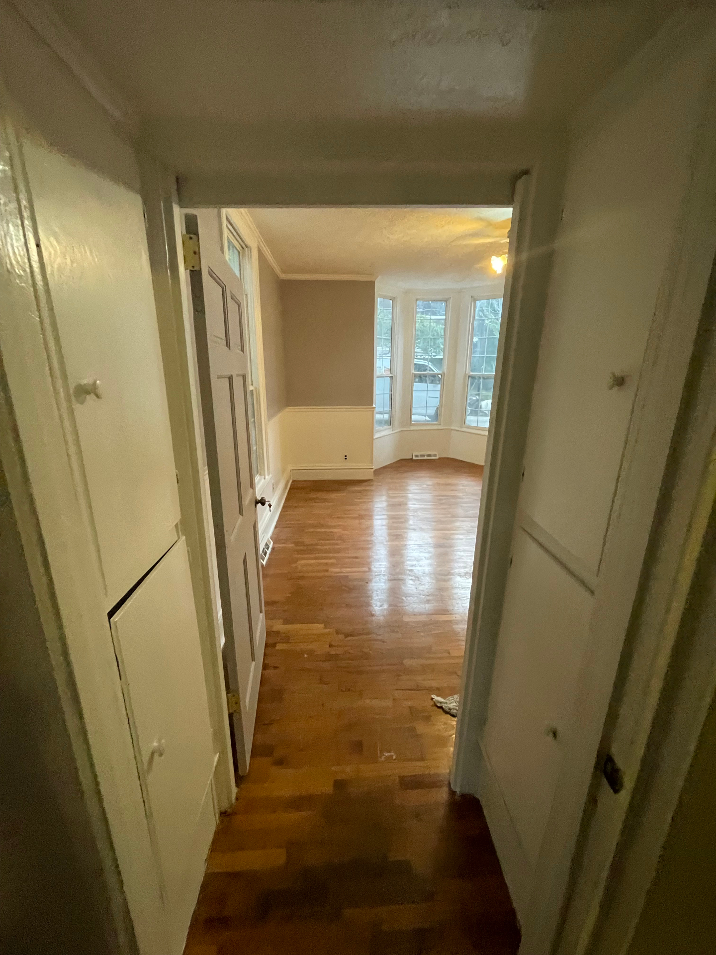 Hallway view leading into renovated room with restored hardwood floors