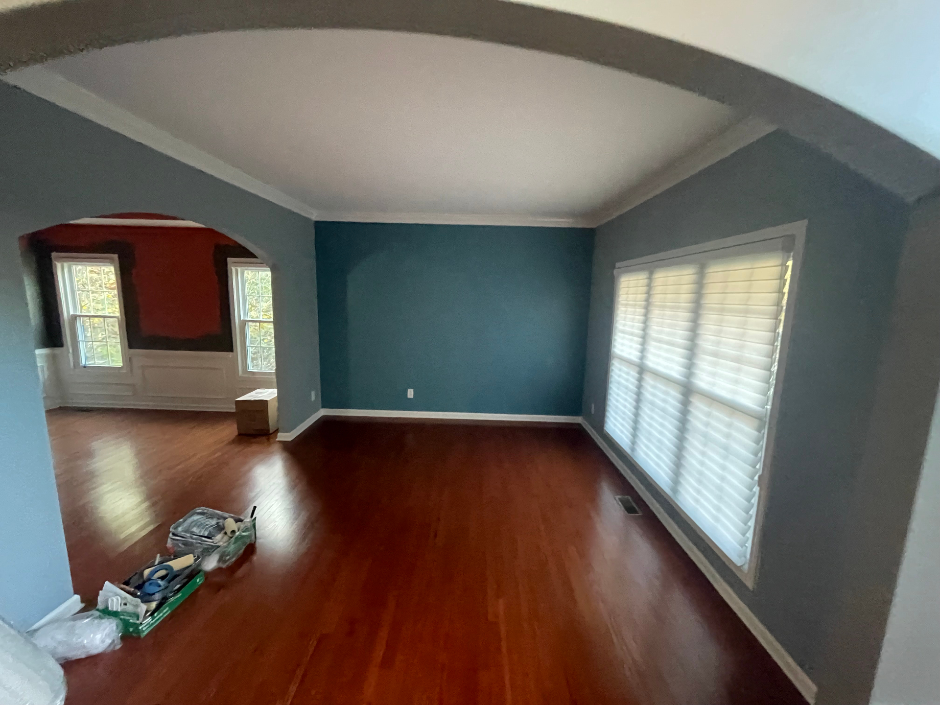 Living room with teal accent wall, gray walls, white trim, and refinished hardwood floors
