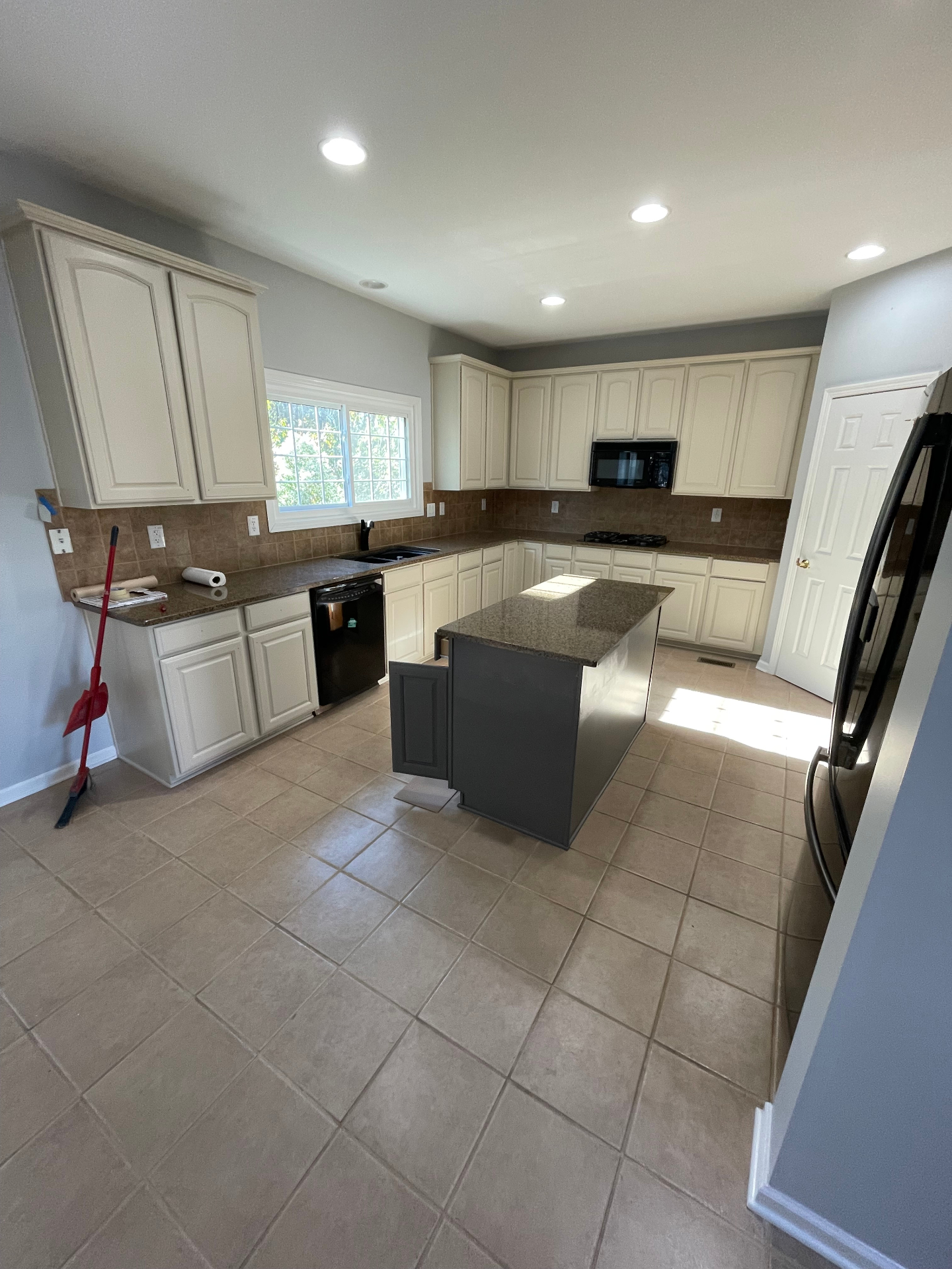 Kitchen with cream raised-panel cabinets, granite counters, and tile floors before refresh