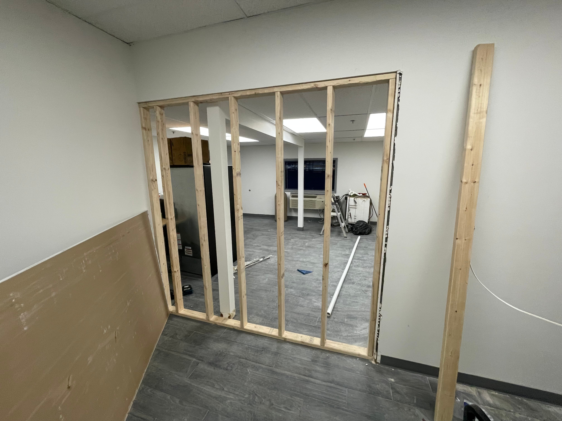 Interior office wall framed with new studs creating a doorway opening in a commercial space