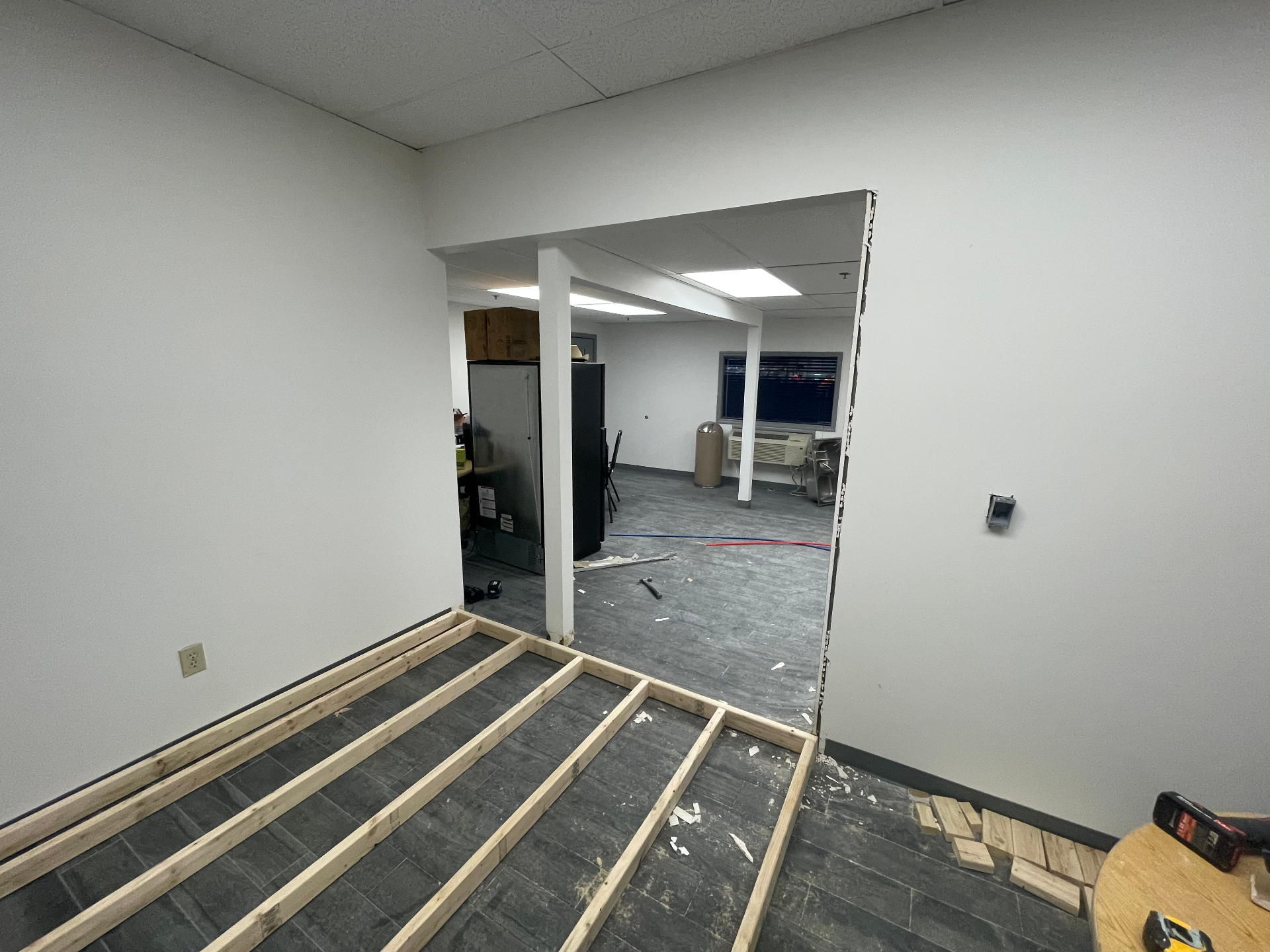Commercial office interior with new wall opening cut and floor joists laid out for buildout