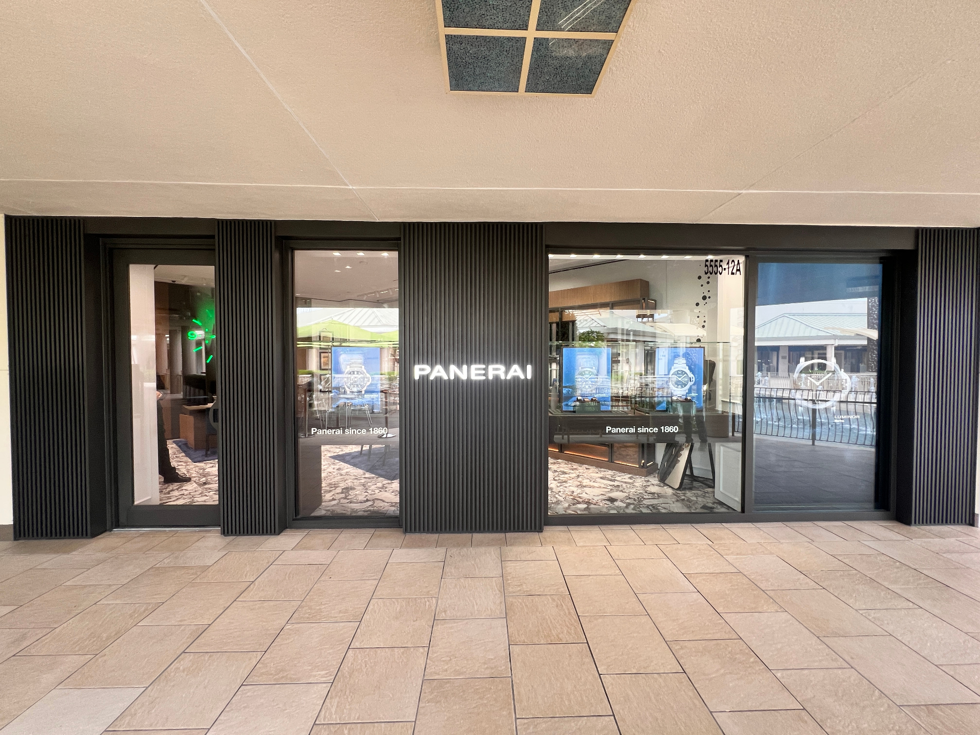 Upscale retail storefront with dark vertical slat paneling and illuminated signage